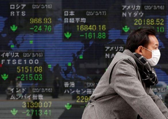 رجل يمر بشاشة إلكترونية تعرض مؤشرات الأسواق الرئيسية في طوكيو يوم 17 مارس 2020. تصوير: إيساي كاتو - رويترز